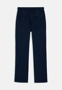 Námořnické modré legíny s volným střihem, elastickým pasem a dvěma kapsami vzadu; hladká textura, jednoduchý design.