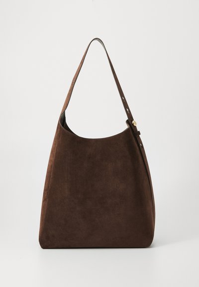 Sac à épaule en daim brun avec une texture douce, un haut arrondi et une bandoulière réglable dotée d'accents de quincaillerie en métal. Design lisse et minimaliste.