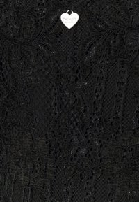 Mustakuvioinen pitsikangas, jossa on kukkakuvioita ja tekstuuripintoja, sekä kiiltäviä koristeita. Hopeanvärinen sydämenmuotoinen tagi, jossa lukee "TWINSSET MILANO", on kiinnitetty.