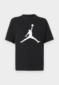 Μαύρο T-shirt με κοντά μανίκια με λευκή σιλουέτα παίκτη μπάσκετ που πηδάει, κρατώντας μια μπάλα πάνω από το κεφάλι σε στάση αστεροπήδησης.