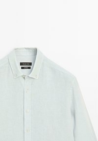 Chemise en lin bleu clair avec un col boutonné, présentant des boutons blancs et un tissu texturé. L'étiquette indique "Massimo Dutti."