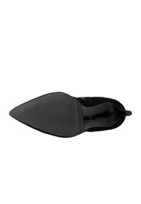 Chaussure en daim noir à bout pointu, avec une finition lisse et texturée, semelle plate et accent de talon en caoutchouc noir. Design minimaliste sans embellissements visibles.