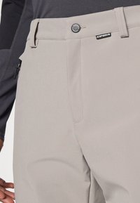 Light gray pants featuring a button closure, front pockets, and a stitched design. Material is smooth with a slim fit around the waist.