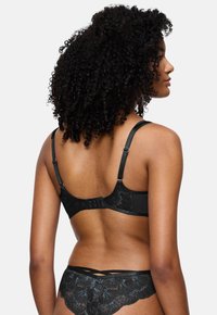 Μαύρο σουτιέν lace με ρυθμιζόμενους ιμάντες, κλείσιμο με γάντζο και μάτι, και λεπτά λουλούδια. Λείος υφασμένος με διακριτική γυαλάδα.