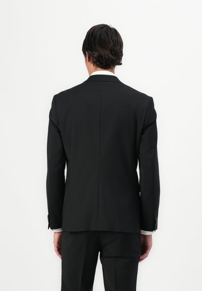 Veste de costume noire ajustée avec un design épuré, des épaules structurées, une fente arrière et des détails de poignet agrémentés de boutons.