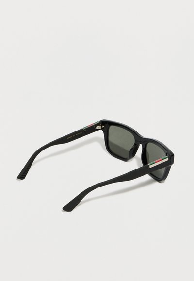 Μαύρα ορθογώνια γυαλιά ηλίου με σκοτεινούς φακούς και μικρές διακοσμήσεις με την ιταλική σημαία στα πλαϊνά, εμφανιζόμενα από πίσω γωνία.