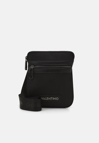 Borsa a tracolla nera realizzata in nylon texturizzato, con una tasca frontale con zip e una tracolla con logo "VALENTINO" in un motivo ripetuto.