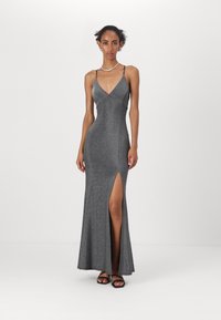 Rochie maxi sclipitoare gri cu un corset ajustat, decolteu adânc în V, bretele subțiri ajustabile și fanta pe coapsă, asortată cu sandale negre.