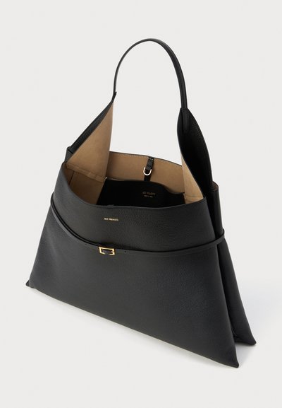 Bolso tote de cuero negro con una textura suave, interior amplio y una silueta estructurada. Presenta un acento de hardware en tono dorado y un forro beige.