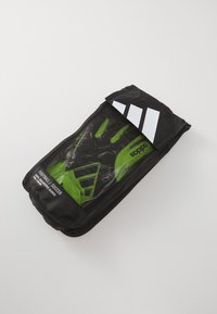 Green goalkeeper gloves in a transparent plastic pouch with a black zipper and three white stripes on top. Packaging labeled "Football Soccer."