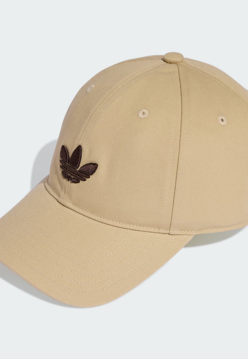Beige Baseballkappe aus Stoff mit gebogenem Schirm. Auf der Vorderseite befindet sich ein dunkelbraunes, gesticktes Logo sowie Belüftungsösen.