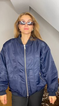 Merineeriline pommjakett läikivast kangast, millel on ees tõmblukk, ribikraanid ja küljetaskud, lõdvestatud lõige ning struktureeritud kaelus.