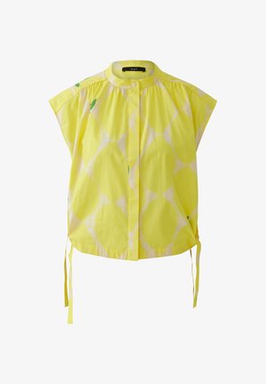 Gelbe Bluse mit kurzen Ärmeln, dezentem weißem Kreis-Muster, Mandarin-Kragen, Knopfleiste und seitlichen Bändern am Saum.