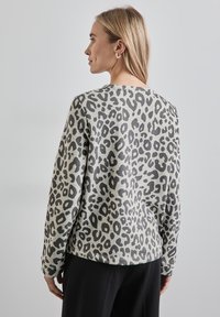Felpa con stampa leopardata in grigio chiaro con macchie grigie scure. Presenta un colletto rotondo e maniche lunghe, realizzata in tessuto morbido e texture.
