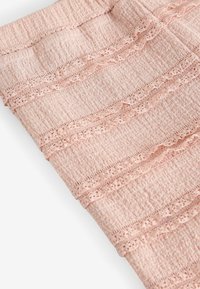 Tissu rose clair avec tricot texturé et détail de bordure en dentelle horizontale, présenté plié sur fond blanc.