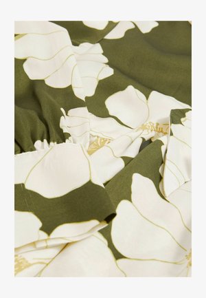 Tkanina s cvjetnim uzorkom koja prikazuje velike bijele cvjetove na tamnozelenoj pozadini, s glatkom teksturom i naboranim rubovima.