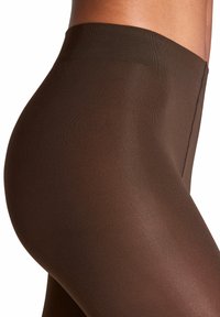 Collant marroni trasparenti con una texture liscia, vita alta e una leggera lucentezza. Cuciture interne visibili lungo il lato.