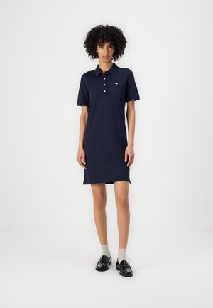 Navy polo dress with short sleeves, three-button placket, and a small logo. Smooth texture, slightly fitted design, knee-length hem.