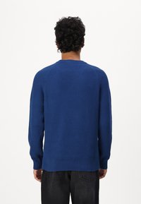 Blauer, gerippter Pullover mit langen Ärmeln, Rundhalsausschnitt und lässiger Passform. Verfügt über ein strukturiertes Muster und einen geraden Saum auf Taillenhöhe.