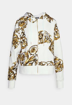 Biała bluza z kapturem na suwak z ozdobnymi barokowymi wzorami kwiatowymi w kolorach złotym i czarnym oraz białymi sznureczkami przy kapturze.