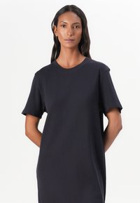 Marineblaues Kurzarmkleid mit rundem Ausschnitt, aus strukturiertem Stoff gefertigt, mit geradem Schnitt und leicht gesenkten Schultern.