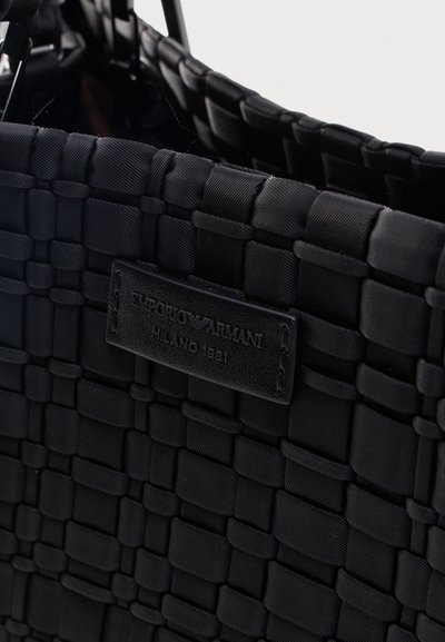 Μαύρη υφασμάτινη υφαντή τσάντα με ραμμένη δερμάτινη ετικέτα Emporio Armani Milano 1981 μπροστά.