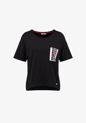 Zwart T-shirt met korte mouwen en een witte zak op de linkerborst, bedrukt met herhaalde "BLAH"-tekst en een rode lippenafbeelding.