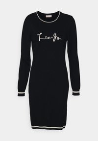 Zwarte gebreide jurk met lange mouwen, een ronde halslijn en contrasterende ivoorkleurige bies aan de kraag en manchetten. Draagt "Liu-Jo" in sierlijk schrift.