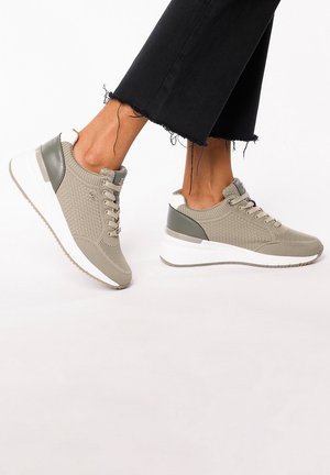 Baskets en tricot beige avec des accents verts, design à lacets et une épaisse semelle intermédiaire blanche. Tige texturée avec un talon lisse et contrasté.