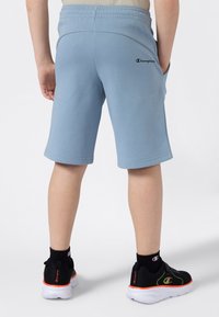 Svetle modré krátké kalhoty po kolena z jemného materiálu, s elastickým pasem a malým černým logem na zadní straně.