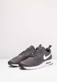 Nike sneakers, gray with mesh and synthetic materials, featuring a white logo, round toe, textured design, and rubber sole with visible air unit.