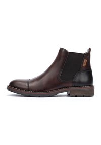 Bottine Chelsea en cuir marron avec des côtés élastiques, bout rond et talon noir contrastant. Détails cousus et une languette à l'arrière.