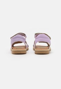 Fioletowe sandały z dwoma regulowanymi paskami, miękką wyściółką wewnętrzną i podeszwą na koturnie owiniętą jutą. Otwarty design pięty zapewnia oddychalność.
