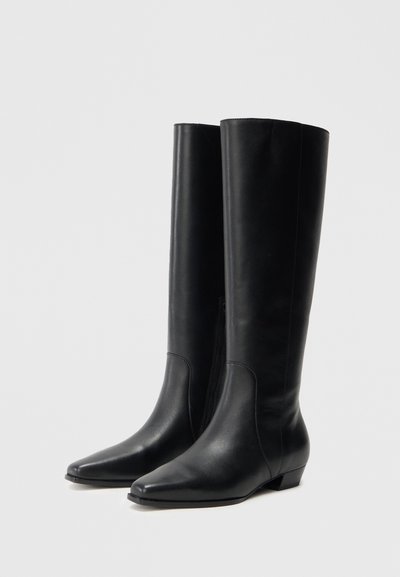 Čierne kožené čižmy po kolená s špicatou špičkou a nízkym blokovým podpätkom. Majú elegantný dizajn a bočný zips pre jednoduché obúvanie.