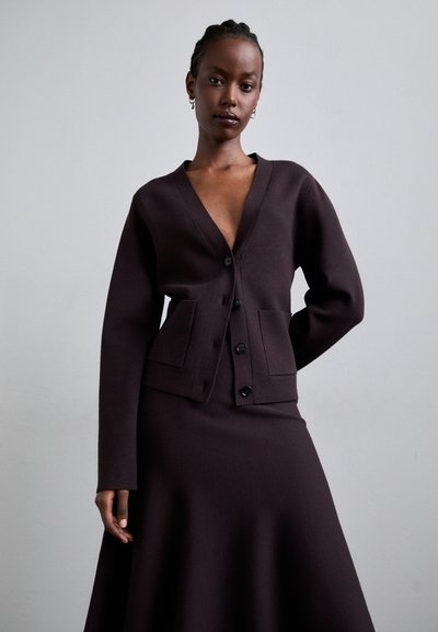 Brown wool blend cardigan with a deep V-neck, long sleeves, five-button closure, and two front pockets, paired with a matching skirt.