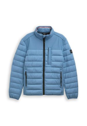 Svetlo modra prešita jakna s črnim sprednjim zadrgo, dvema stranskima žepoma z zadrgo, enim navpičnim žepom na prsih in stoječim ovratnikom.