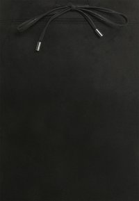 Jupe en daim noir avec une taille à cordon avec des embouts métalliques. Sa texture lisse et ses lignes épurées créent un design minimaliste.