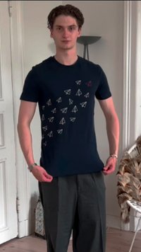 Camiseta de color azul oscuro con múltiples gráficos de aviones de papel en blanco y gris claro. Tiene un cuello redondo y mangas cortas.