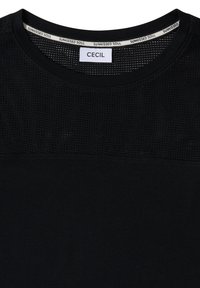 Haut noir avec partie supérieure en maille, encolure ronde et étiquette de marque « CECIL » à l’intérieur du col avec le texte répété « SUNKISSED SOUL ».