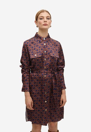 Vestido camisero de manga larga en marino con un patrón geométrico naranja, presenta cierres de botones y un lazo en la cintura. Dos bolsillos en el pecho añaden detalle.