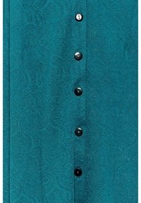 Koszula w kolorze morskim o fakturowanej tkaninie z wzorem oraz sześcioma czarnymi guzikami na przodzie, podkreślająca jej szczegółowy design i kolor.