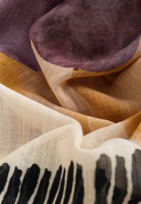 Farverigt letvægtsstof med et blandet mønster af lilla, guld og elfenben med en gradient og uregelmæssige sorte accenter.