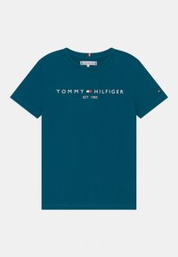 Teal puuvillainen t-paita, jossa on pyöreä kaula-aukko, lyhyet hihat ja valkoinen "TOMMY HILFIGER EST. 1985" -logo, punaisilla ja valkoisilla korosteilla.