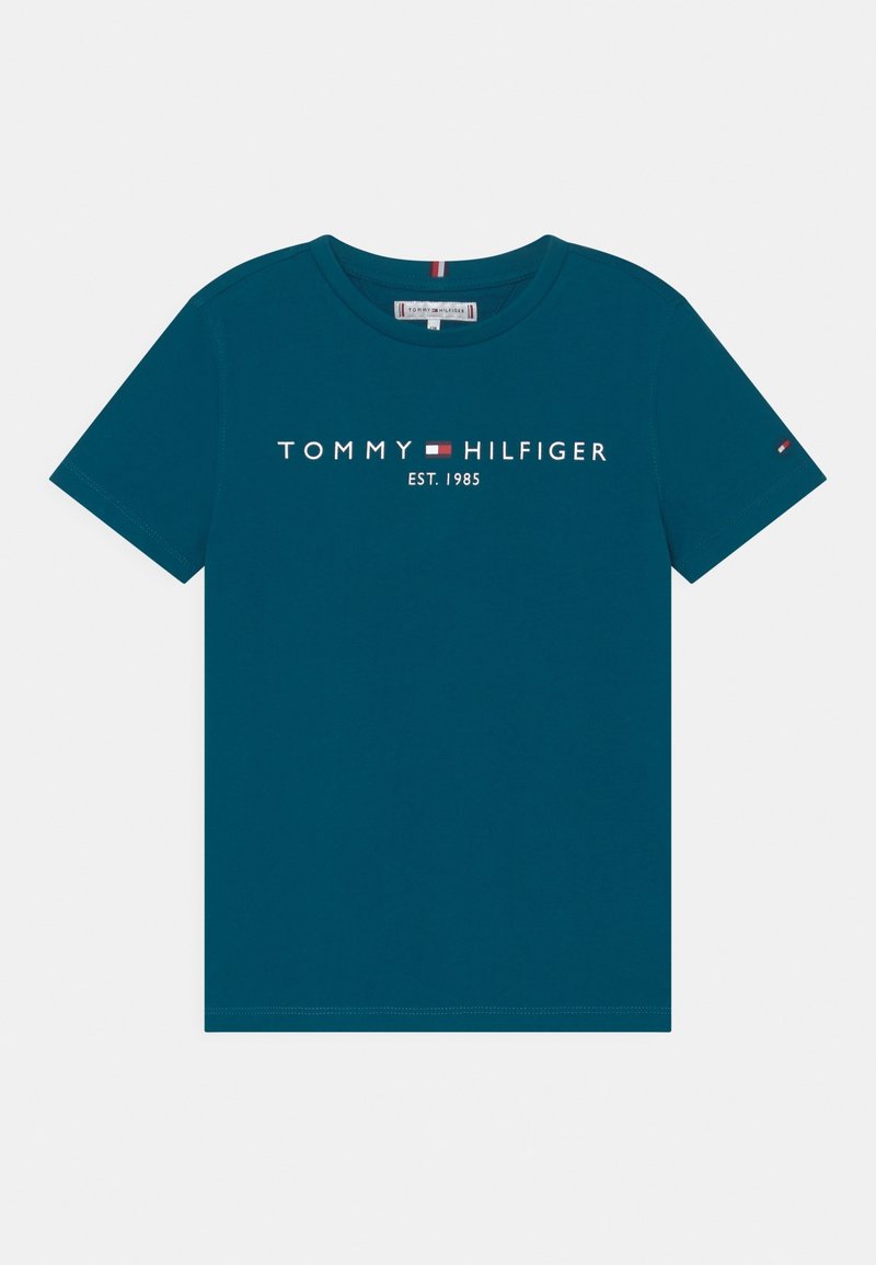 Teal puuvillainen t-paita, jossa on pyöreä kaula-aukko, lyhyet hihat ja valkoinen "TOMMY HILFIGER EST. 1985" -logo, punaisilla ja valkoisilla korosteilla.