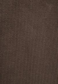 Brauner Cordstoff mit vertikalen Riffelungen, weicher Textur und gleichmäßigem Muster, geeignet für Polster- oder Bekleidungsanwendungen.