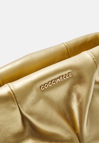 Złota metaliczna torba ze skóry z marszczonym wzorem. Posiada subtelne wytłoczenie nazwy marki oraz gładką, refleksyjną teksturę.