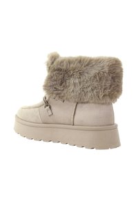 Beżowe botki za kostkę z mankietem z imitacji futra, wykonane z zamszu, zaokrąglony nosek oraz gruba gumowa podeszwa z teksturowanym wzorem zapewniającym przyczepność.
