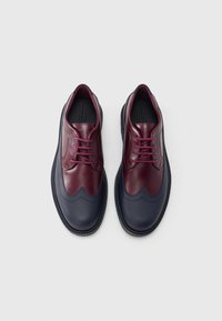 Bordó és tengerészkék bőrcipők hullámos mintával, kerek orral és fűzős rögzítéssel. Gumi külső talp részletes varrással.