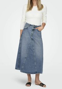 Jeansmaxikjol med hög midja, med paneldesign, ljusblå färg och rå nederkant. Kombinerad med svarta slidesandaler.