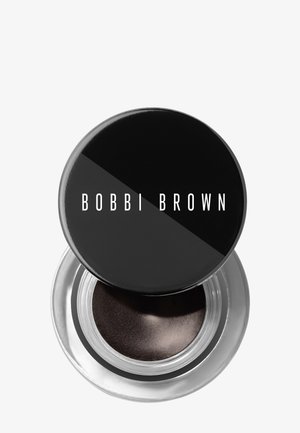Piccolo barattolo trasparente di ombretto cremoso marrone scuro con coperchio nero parzialmente aperto con etichetta Bobbi Brown su sfondo bianco.